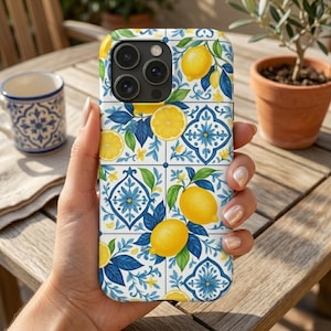 Puede incluir: Funda de teléfono con diseño de limones y hojas. La funda tiene un diseño de azulejos con limones amarillos, hojas azules y detalles florales. La funda del teléfono está en la mano de una persona.