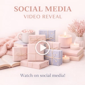 Puede incluir: Imagen promocional con el texto "SOCIAL MEDIA VIDEO REVEAL" y "Watch on social media!". La imagen presenta regalos envueltos, velas, una taza de malvaviscos y un jarrón de flores, todo en tonos rosa y blanco.