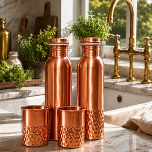 May include: Two tall, cylindrical copper water bottles with matching screw-top lids and two shorter, matching copper tumblers. The lower sections of the tumblers and one bottle feature a textured, hammered finish with a decorative beaded band.