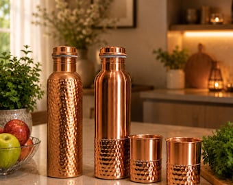 May include: Two copper water bottles and two matching copper cups. One bottle has a fully hammered texture, while the other bottle and both cups feature a smooth upper section and a hammered lower section with a beaded rim detail.
