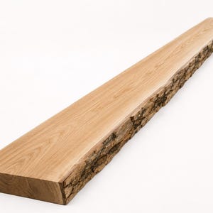 May include: A long, rectangular wooden shelf featuring a smooth, light brown finished top surface with a visible wood grain pattern and one side edge left in its natural, rough, and textured bark state, showcasing the raw edge of the timber.
