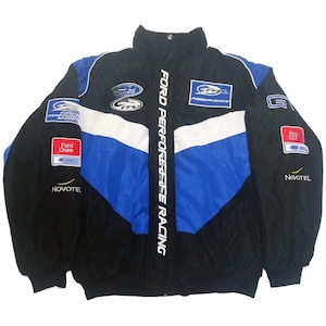 Op de afbeelding: Zwarte, blauwe en witte Ford Performance Racing jas. De jas heeft verschillende logo's, waaronder "Ford", "FP" en "Novotel". De tekst "FORD PERFORMANCE RACING" staat verticaal op de voorkant.
