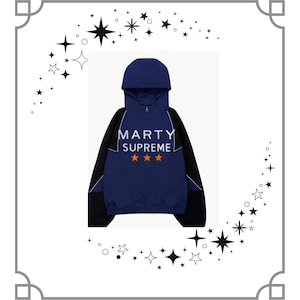 Könnte beinhalten: Eine marineblaue Kapuzenjacke mit dem weißen Text "MARTY SUPREME" und drei orangefarbenen Sternen. Die Jacke hat schwarze Ärmel mit weißen Akzenten und eine marineblaue Kapuze.