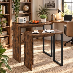 May include: A set of two nesting tables featuring a dark brown wood grain finish and black metal frames. The tables have a rectangular design with clean lines, providing a functional surface for items like a white cup and an open magazine.