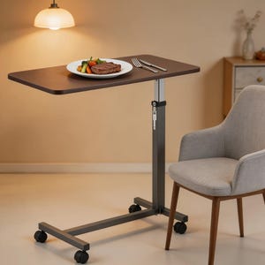 May include: A brown, height-adjustable overbed table with a rectangular top. The table has a dark gray metal frame with wheels and a plate of food on top. A gray chair is next to the table.