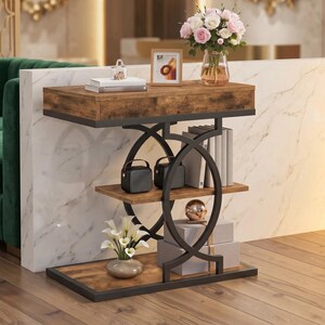 May include: A console table with a rustic brown wood finish and a black metal frame featuring circular side supports. The table has a top surface, a middle shelf, and a bottom base, holding books, a small picture frame, a vase of flowers, and boxes.