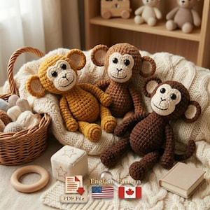May include: Three crocheted monkey plush toys in shades of brown and yellow are arranged on a cream-colored knitted blanket. The monkeys have white faces and smiling expressions. A wooden basket and other toys are in the background.