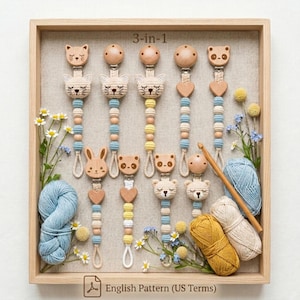 Puede incluir: Una bandeja de madera exhibe varios clips para chupete de bebé 3 en 1 con diseños de animales. Los clips presentan ganchillo y cuentas de madera en colores pastel. La bandeja también incluye hilo, flores y un ganchillo. El texto "English Pattern (US Terms)" es visible.