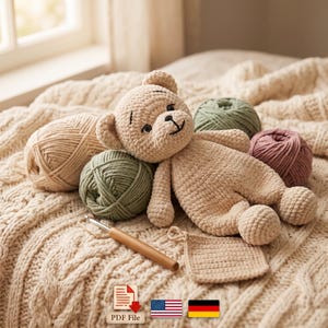 Peut inclure: Un ours en peluche crocheté beige entouré de plusieurs pelotes de laine dans des tons beige, vert sauge et vieux rose. Un crochet à manche en bois et un petit échantillon carré crocheté sont placés à proximité de l'ours.