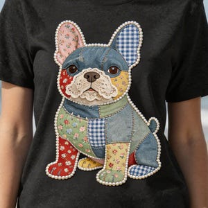 May include: Black t-shirt with a patchwork French Bulldog design. The dog features floral, gingham, and solid patches in red, blue, yellow, and green. The design is outlined with a pearl trim.