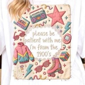 Può includere: T-shirt bianco con un design retrò colorato. Il design include una stella rosa, un boombox, occhiali da sole, una giacca, pattini a rotelle e il testo "please be patient with me, I'm from the 1900's".