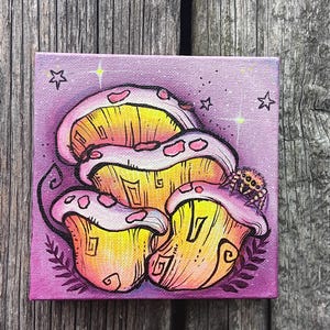 May include: A square canvas painting featuring a cluster of three mushrooms with yellow caps and pinkish-purple edges. A small spider sits on the right mushroom. The background is a gradient of purple with hand-drawn stars and small leaf motifs.