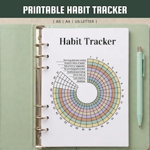 Peut inclure: Une page de suivi d'habitudes imprimable dans un classeur vert clair avec un stylo assorti. La page présente un graphique circulaire avec le texte Habit Tracker et liste des tâches quotidiennes comme Morning skincare routine et Meditate.