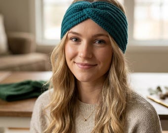 May include: A teal knitted headband with a twisted knot design. The headband is made of a textured yarn and is worn by a person with blonde hair. The person is wearing a beige jumper and a gold necklace.