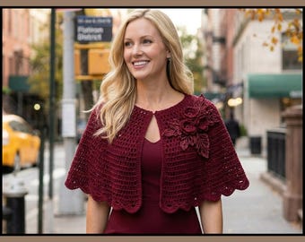 May include: A deep burgundy crochet capelet featuring a scalloped hem and a cluster of three-dimensional floral embellishments on the left side. The garment is worn over a matching dark red top. The text Crochet Floral Capelet Pattern is visible.