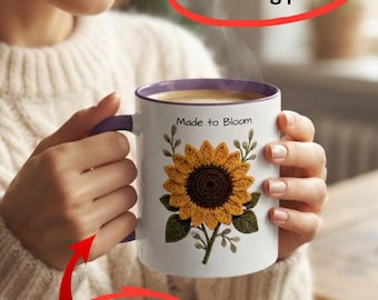 May include: A white ceramic mug with a purple rim and handle, featuring a graphic of a yellow sunflower with green leaves and the text Made to Bloom. The mug has a sturdy handle and a vibrant, long-lasting print of the floral design.