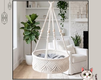 May include: A hanging cradle featuring off-white macrame cord with intricate knot patterns and wooden beads. The circular structure is suspended by four braided cords meeting at a top ring. The text Crochet Cradle Pattern Instant Download is visible.