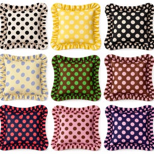 May include: Nine decorative throw pillows with ruffled edges. Each pillow features a polka dot pattern in various color combinations, including black and white, yellow and white, and navy with red.
