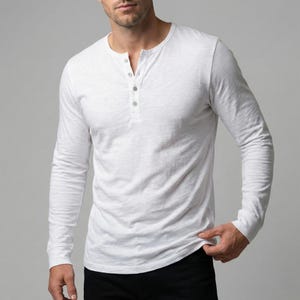 以下が含まれることがあります： 3つボタンの前立てが付いた、白の長袖ヘンリーシャツ。 シャツはクルーネックで、柔らかく質感のある生地で作られています。 袖は長く、フィット感があります。 シャツは無地の白です。