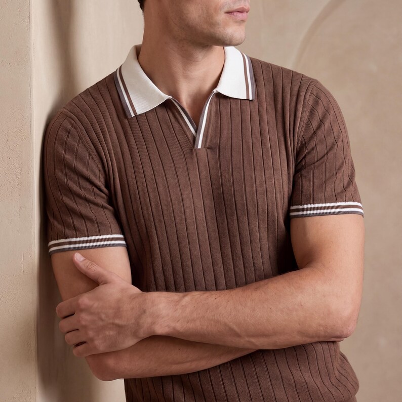 Puede incluir: Polo marr&oacute;n acanalado con cuello y ribete de manga blancos. La camisa tiene cuello en V y mangas cortas. La camisa est&aacute; hecha de un material suave y acanalado.