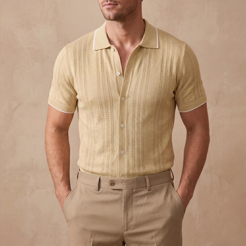 May include: A light tan polo shirt with short sleeves and a button-down front. The shirt has a textured pattern and white trim on the collar and sleeves. The model is also wearing tan pants.