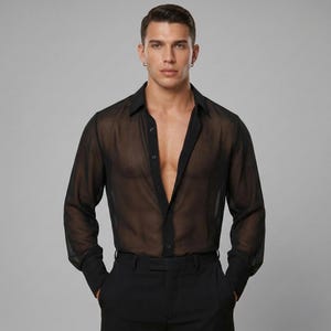 May include: A see-through black shirt with long sleeves and a standard collar. The shirt is partially unbuttoned. The model is wearing black trousers. The background is a plain grey.