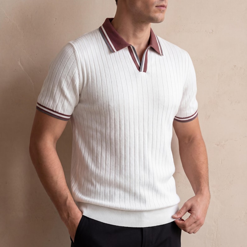 Puede incluir: Polo blanco acanalado con mangas cortas. La camisa tiene un cuello y pu&ntilde;os a rayas burdeos y blancos. El polo tiene un dise&ntilde;o de cuello en V y una textura acanalada.