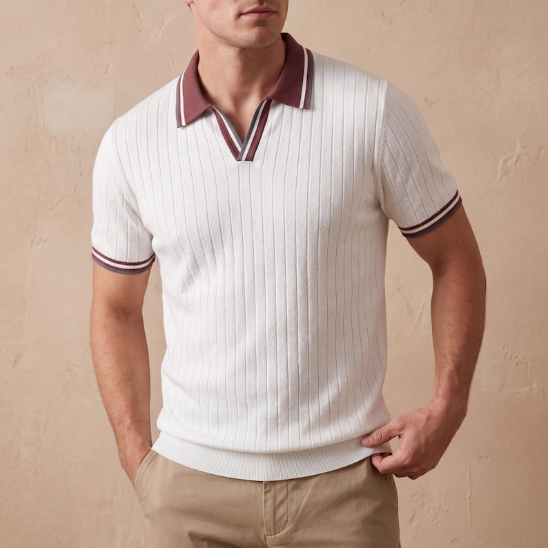 Puede incluir: Polo acanalado color crema con cuello en V. El cuello y los pu&ntilde;os de las mangas tienen un ribete burdeos y blanco. La camisa de manga corta tiene un corte entallado. El modelo lleva pantalones color caqui.