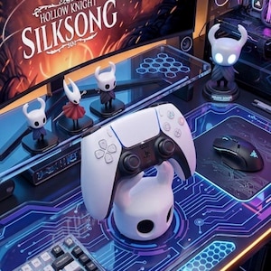 May include: A gaming setup featuring a curved monitor displaying "Hollow Knight: Silksong" and various figurines. A white PlayStation 5 controller rests on a matching stand. A keyboard and mouse are also present, with a blue and purple circuit board design.