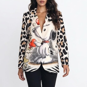 Könnte beinhalten: Ein Blazer mit Leopardenmuster an den Ärmeln und einer grafischen Illustration eines weißen Zeichentrickhundes mit einem roten Herz auf der Vorderseite, kombiniert mit einer schlichten schwarzen Hose und schwarzen Schuhen mit spitzer Zehenpartie.