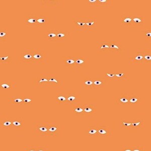 May include: Orange fabric with a repeating pattern of cartoon eyes. Each eye has a white iris, a black pupil, and a purple or black upper eyelid. The fabric is from Ruby Star Society.