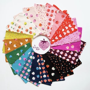 May include: A collection of fabric squares arranged in a circular pattern, each featuring a different strawberry print. The fabrics vary in color, including pink, red, green, and blue, with white strawberries and other designs. The center has a strawberry logo with the text "strawberry" and "by Kimberly Knight".
