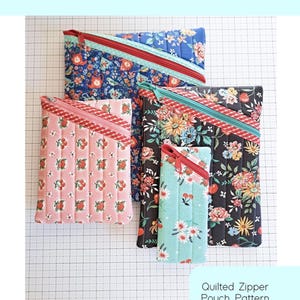 May include: A collection of quilted zipper pouches in various floral patterns, including a pink cherry print, blue floral, and black floral designs. The pouches have contrasting colored zippers and are labeled "Hemingway Pouch" and "Quilted Zipper Pouch Pattern in Four Sizes."