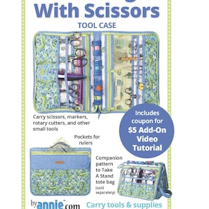 May include: A fabric tool case titled Running With Scissors featuring a green and blue patterned exterior. The open case displays multiple interior pockets, elastic loops, and mesh compartments designed to hold scissors, markers, and rotary cutters.