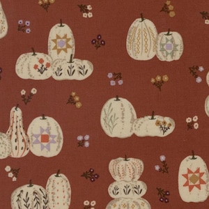 May include: A fabric pattern featuring off-white pumpkins and gourds scattered across a deep terracotta background. The pumpkins are decorated with various motifs including geometric star shapes, small floral sprigs, and vertical line patterns.