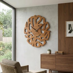 May include: A large, round wooden wall clock with cut-out numbers. The clock has black hands and is mounted on a light grey wall. The clock's natural wood grain adds a warm, organic feel to the modern design. The clock is approximately 61 cm in diameter.
