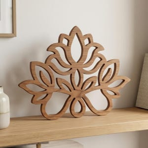 Peut inclure: Une décoration murale en bois brun présentant un motif découpé symétrique inspiré d'une fleur ou d'un lotus. L'objet possède une finition en bois naturel lisse et se compose de formes de pétales incurvées et interconnectées en étages.