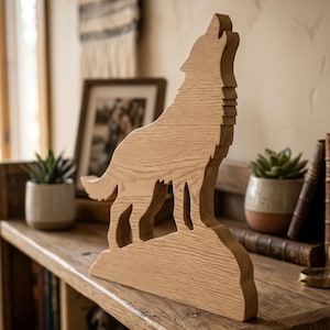 May include: A wooden sculpture of a howling wolf, crafted from light-colored wood. The wolf is depicted in a stylized, three-dimensional form, with its head raised in a howl. The sculpture is placed on a wooden shelf, suggesting a decorative item.