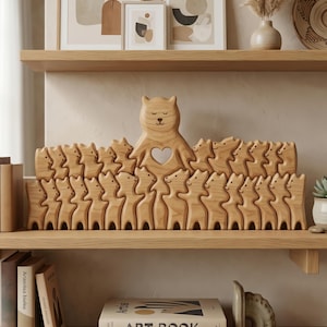 Pode incluir: Uma escultura de madeira de uma família de ursos com um urso grande no centro e ursos menores ao seu redor. O urso grande tem um recorte em forma de coração. A escultura é feita de madeira clara e está em uma prateleira de madeira.