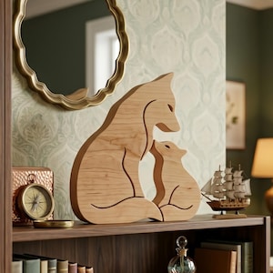 Peut inclure: Une sculpture en bois représentant un renard et son petit. La sculpture en bois de couleur claire est posée sur une étagère avec d'autres objets décoratifs, dont une boussole, un miroir et un modèle de navire. La sculpture de renard est un charmant objet de décoration.