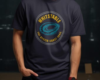 May include: Navy blue t-shirt featuring a circular design with the text "WHITSTABLE" in yellow and "THE OYSTER COAST TRAIL" in gray. The design includes a blue oyster illustration. The shirt is short-sleeved.