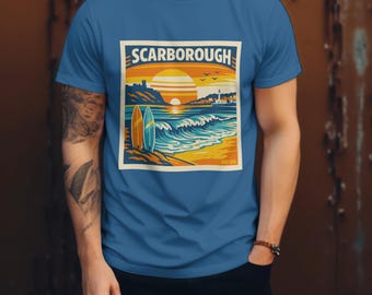 May include: Blue t-shirt featuring a retro-style illustration of Scarborough, with a sunset over the ocean, two surfboards, and the text "SCARBOROUGH". The design is in shades of orange, yellow, blue, and white.
