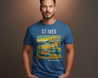 May include: A blue t-shirt featuring a coastal scene with two boats, a lighthouse, and the text "ST IVES" above the image and "The Artisan Coast" below. The shirt is worn by a person.