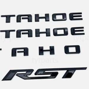 Puede incluir: Juego de emblemas Tahoe y RST negros. Los emblemas Tahoe son letras individuales. El emblema RST es una sola pieza. Todas las piezas tienen un acabado brillante y se muestran sobre un fondo blanco.
