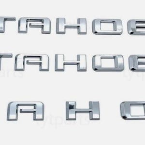 Puede incluir: Tres juegos de letras cromadas "TAHOE", probablemente para un emblema de vehículo. Las letras son robustas y tridimensionales, con una superficie brillante y reflectante. La disposición sugiere un producto para la personalización o reparación automotriz.