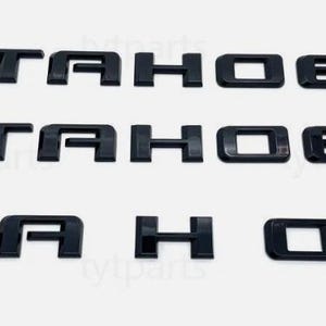 Puede incluir: Letras de plástico negro que deletrean "TAHOE" en tres filas. Las letras están en una fuente en negrita y en bloque, y probablemente son emblemas o calcomanías automotrices. El fondo es blanco liso.