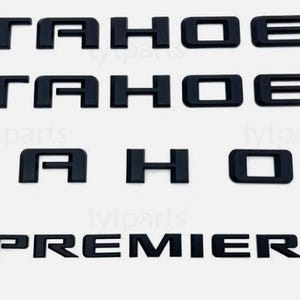 Puede incluir: Emblemas Tahoe y Premier de plástico negro. La palabra "TAHOE" se muestra tres veces y la palabra "PREMIER" una vez. Las letras son en negrita, en una fuente sans-serif.
