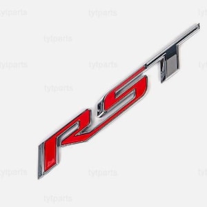 Puede incluir: Un emblema "RS" cromado y rojo, probablemente para un vehículo. Las letras están delineadas en cromo con un interior rojo. El emblema está en ángulo y parece ser de metal, con una superficie brillante y reflectante. El fondo es blanco.