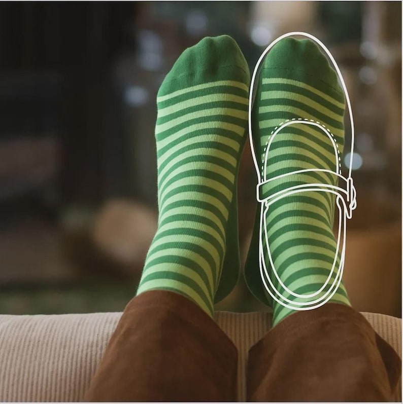 A pair of feet wearing green and white striped socks, with a drawing of a shoe on the right foot.