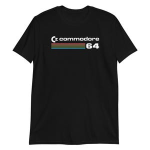 Puede incluir: Camiseta negra con el logotipo de Commodore 64 en blanco. La palabra "commodore" está encima de rayas horizontales en naranja, amarillo y azul. El número "64" está en blanco a la derecha de las rayas.